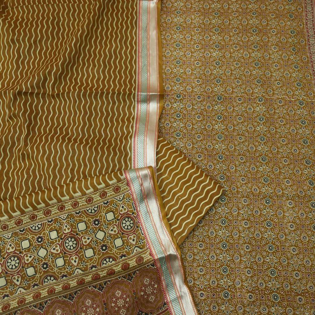 दिपशा Mustard Brown Ajrak Printed Mangalgiri Hem Work Cotton Suit Set