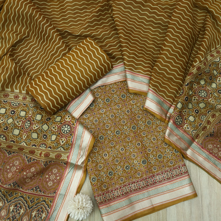 दिपशा Mustard Brown Ajrak Printed Mangalgiri Hem Work Cotton Suit Set